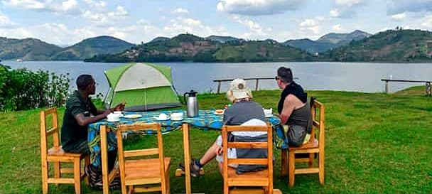 Guests having tea beside their tent above the lake